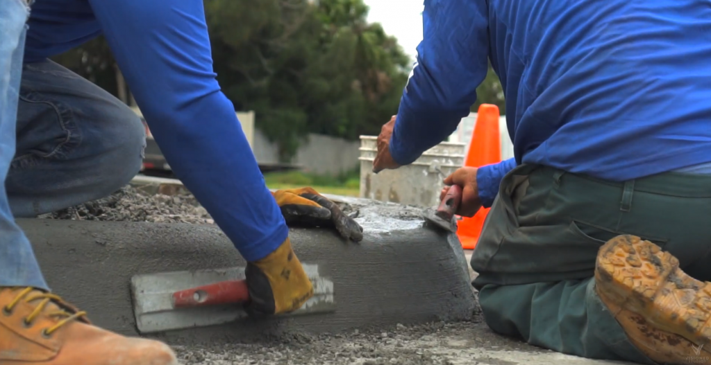 Two men kneeling down polishing a concrete curb