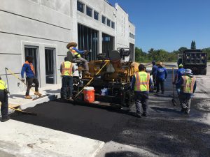 Asphalt Paving Machine working with employees behind wearing reflective vests